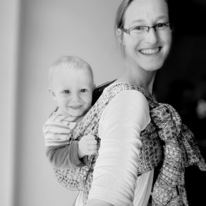 Julia trägt ein Baby sicher im Tragetuch auf dem Rücken während der Tragetuch-Beratung in Freital.